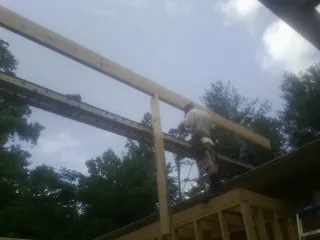 Carpenter setting a ridge beam over a new addition frame — Ice Dam Removal by Roofing Brothers in Cusick