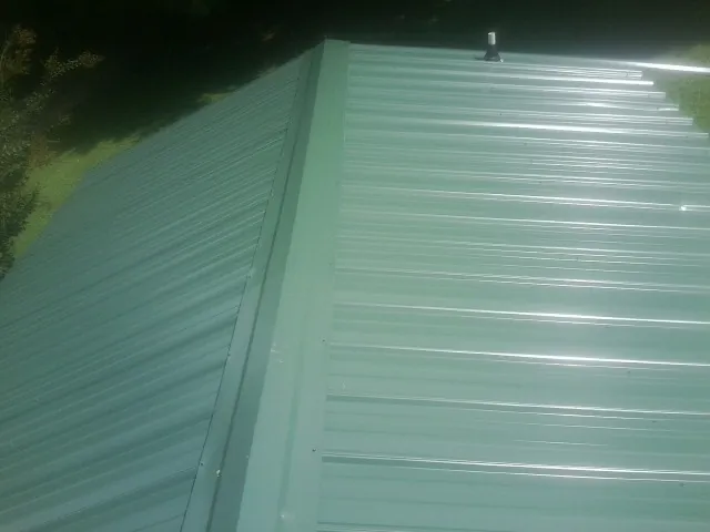 New green metal panels meeting at the ridge of a roof — Flat Roof Repair work by our crew in Cusick