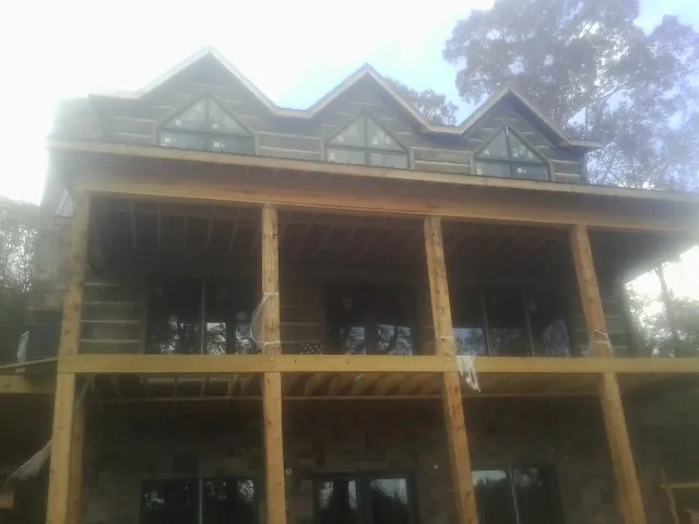 Dormers and porch framing on a large log home under construction — Roof Coating work by our crew in Cusick