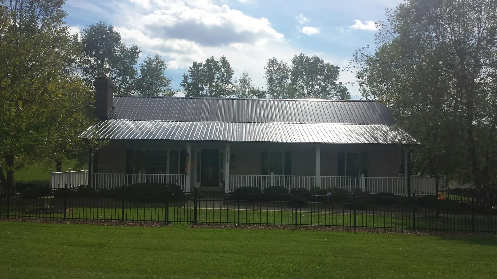 Gray metal roof on a brick ranch with a full width front porch — Gutter Guard Installation work by our crew in Cusick