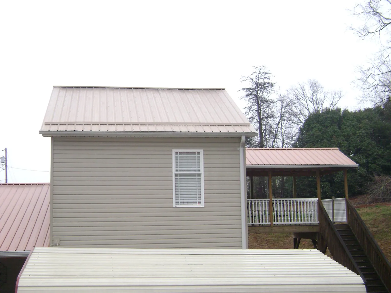 Tan metal roofs on a two story addition and attached porch, from a Roof Replacement job in Cusick