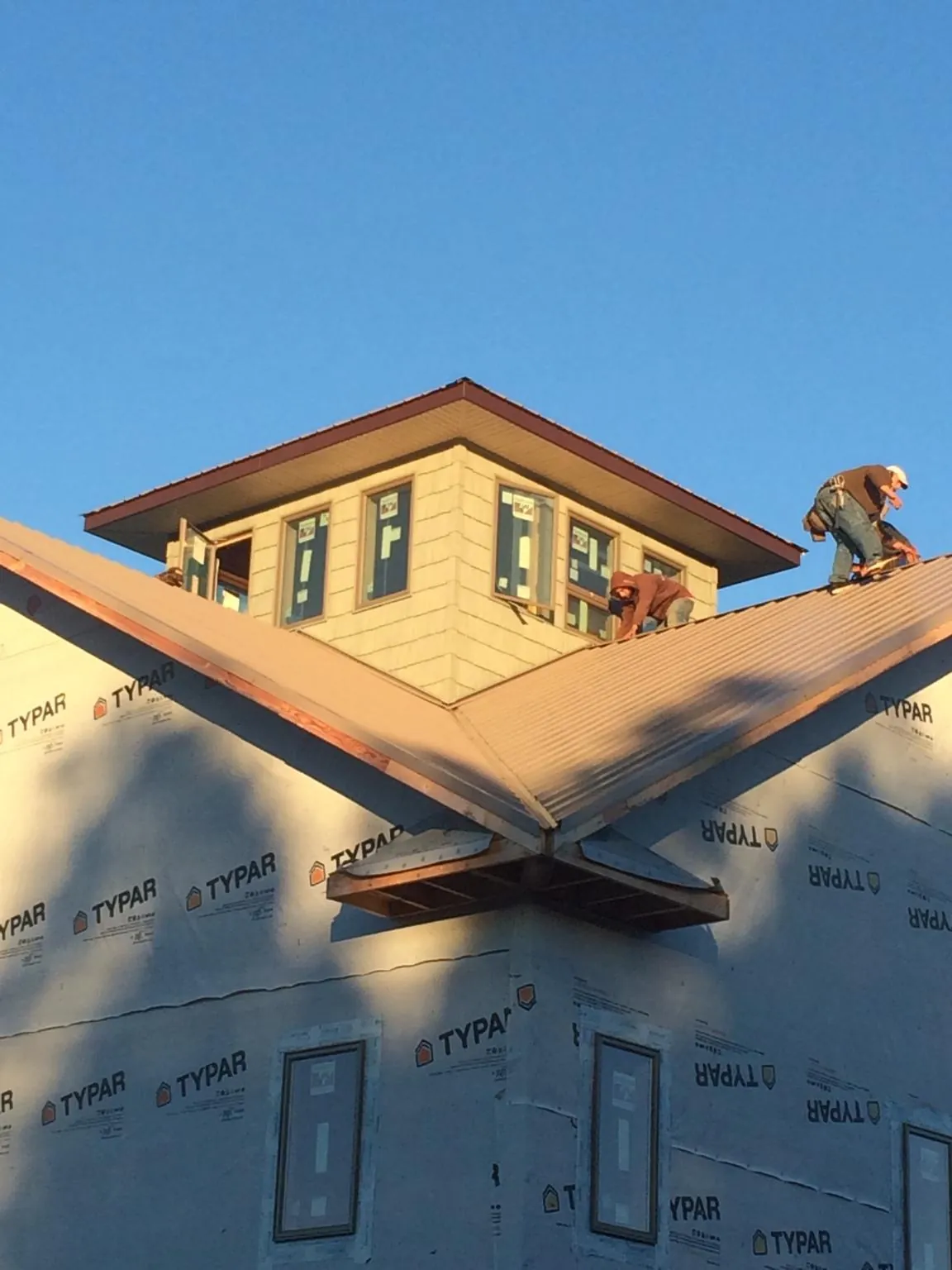Roofers working around a rooftop cupola on a new metal roof at sunset — Roof Waterproofing in Cusick by Roofing Brothers